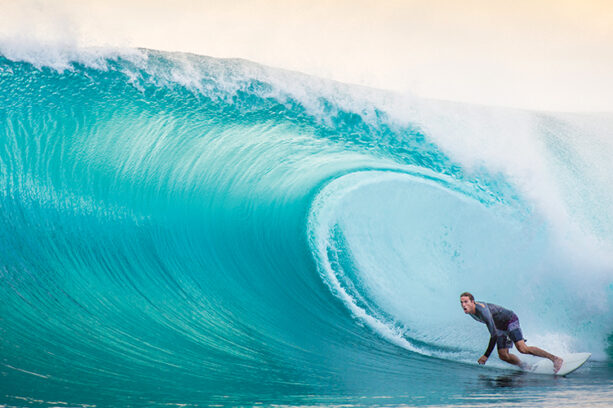 a man surfing alongside a large wave