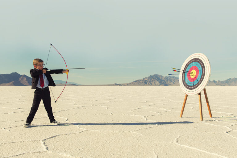small child in suit aiming towards an archery target